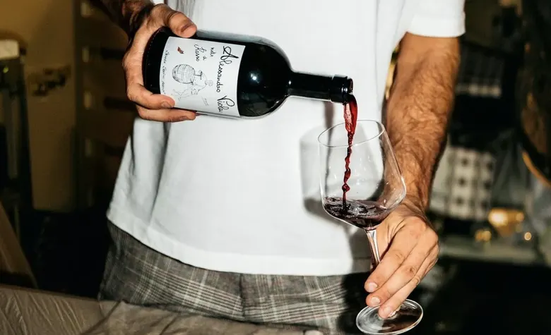 Red wine being poured into a glass at a bar