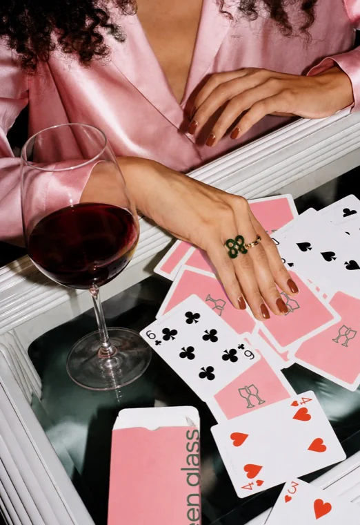 A glass of red wine beside a spread of Green Glass playing cards